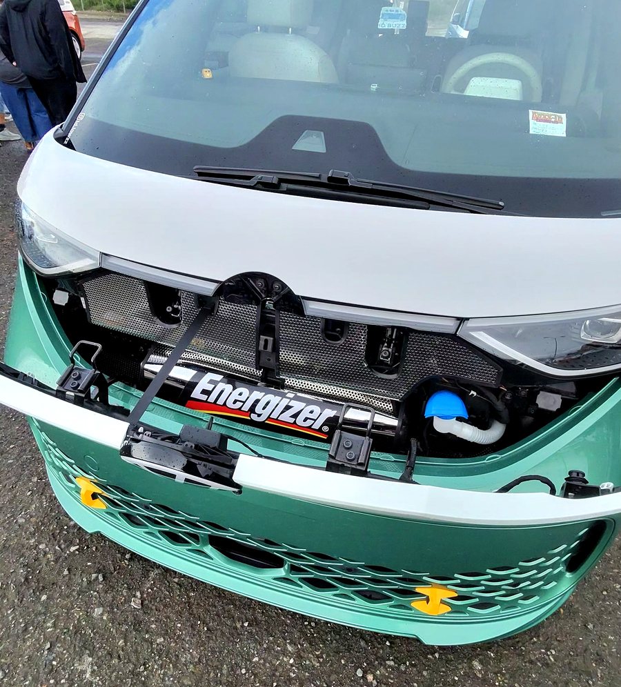 The front fascia panel removed from a lowered teal ID. Buzz, revealing a large Energizer-branded battery mounted behind the grille as a joke.